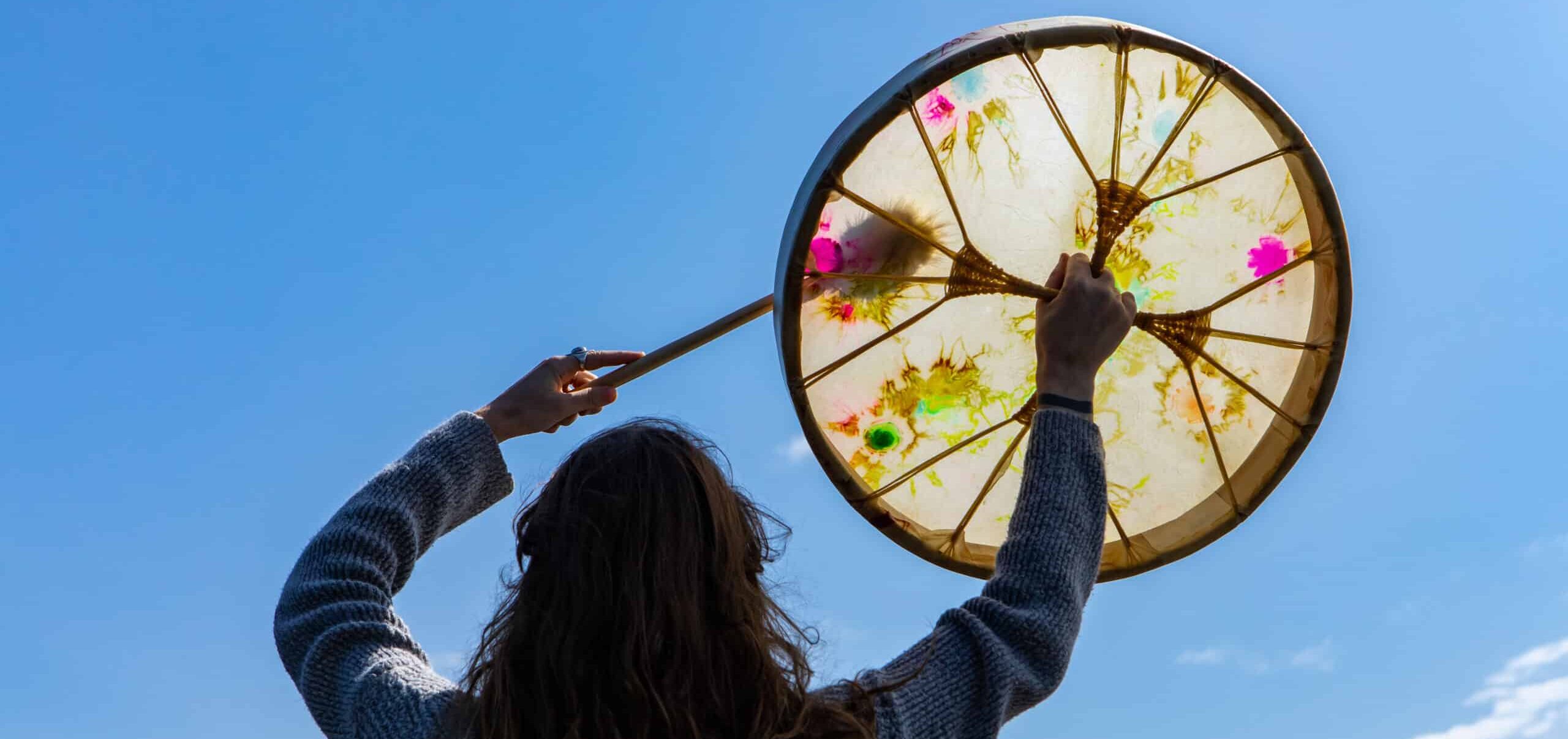 A person holding up a traditional indigenous drum.